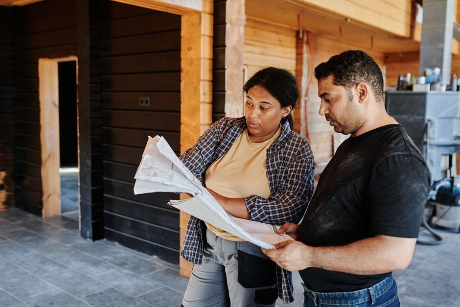 Two people reviewing blueprints inside a wooden building interior