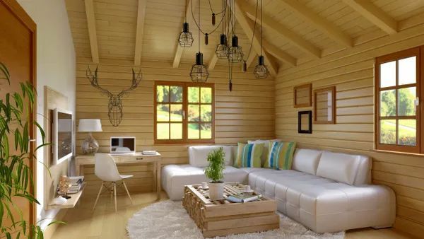 a living room in a wooden cabin with a couch, desk, and television