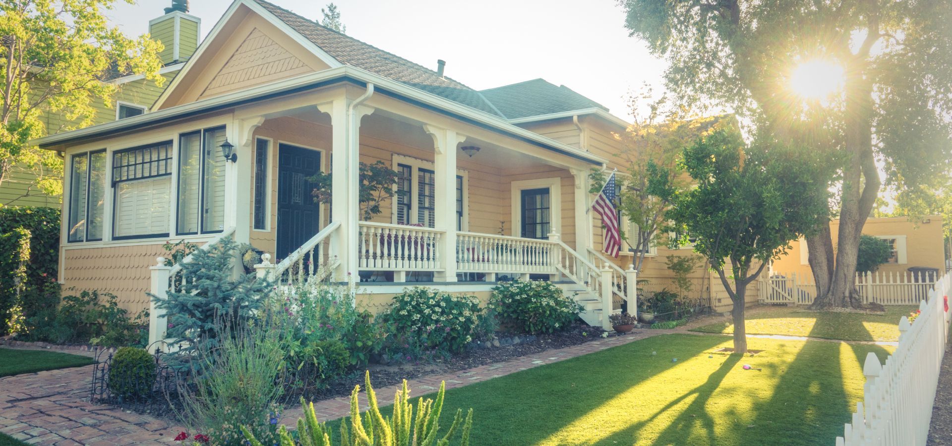 A large house with a large porch and a white picket fence.