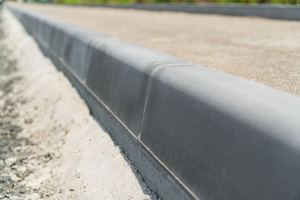 Close-up of a concrete curb edging a sandy roadside