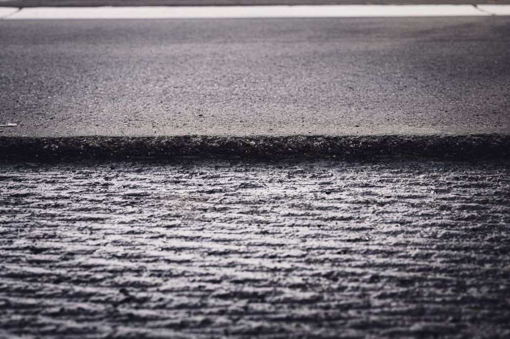Wet asphalt road surface with a white lane marking