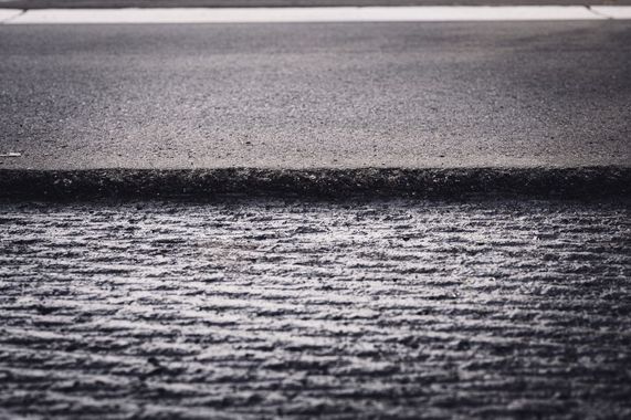 Wet asphalt road surface with a white lane marking