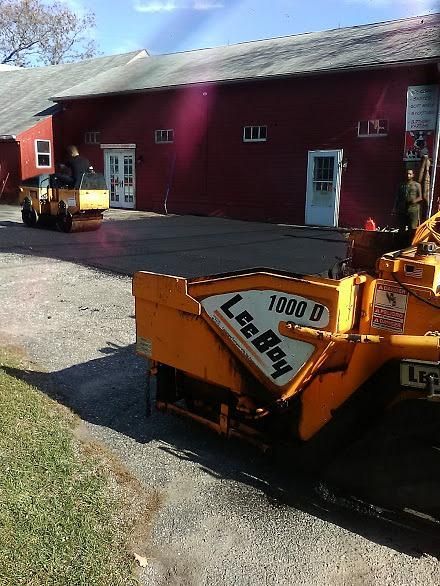 Orange snowplows outside a red building on a sunny day