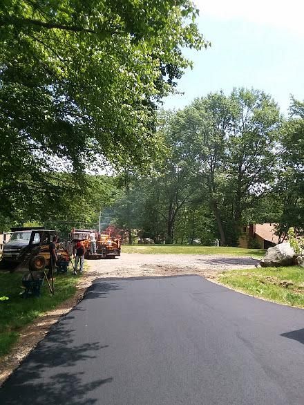Freshly paved driveway beside parked vehicles and trees on a sunny day