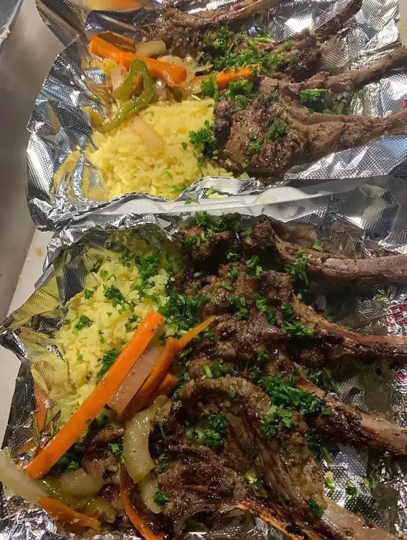 A close up of a plate of food with meat and vegetables on tin foil.