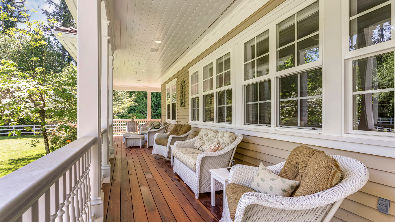 A large porch with wicker chairs , a couch , and a table.