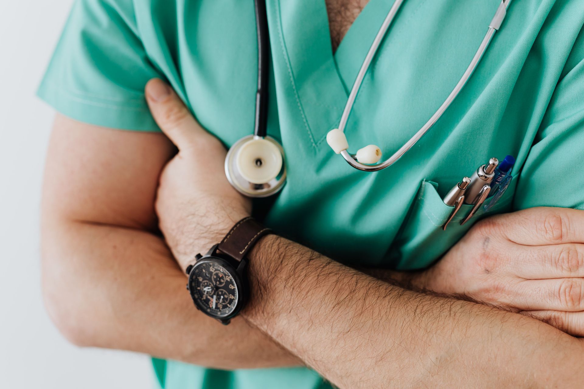 Close-up of a healthcare worker in green scrubs with a stethoscope and crossed arms