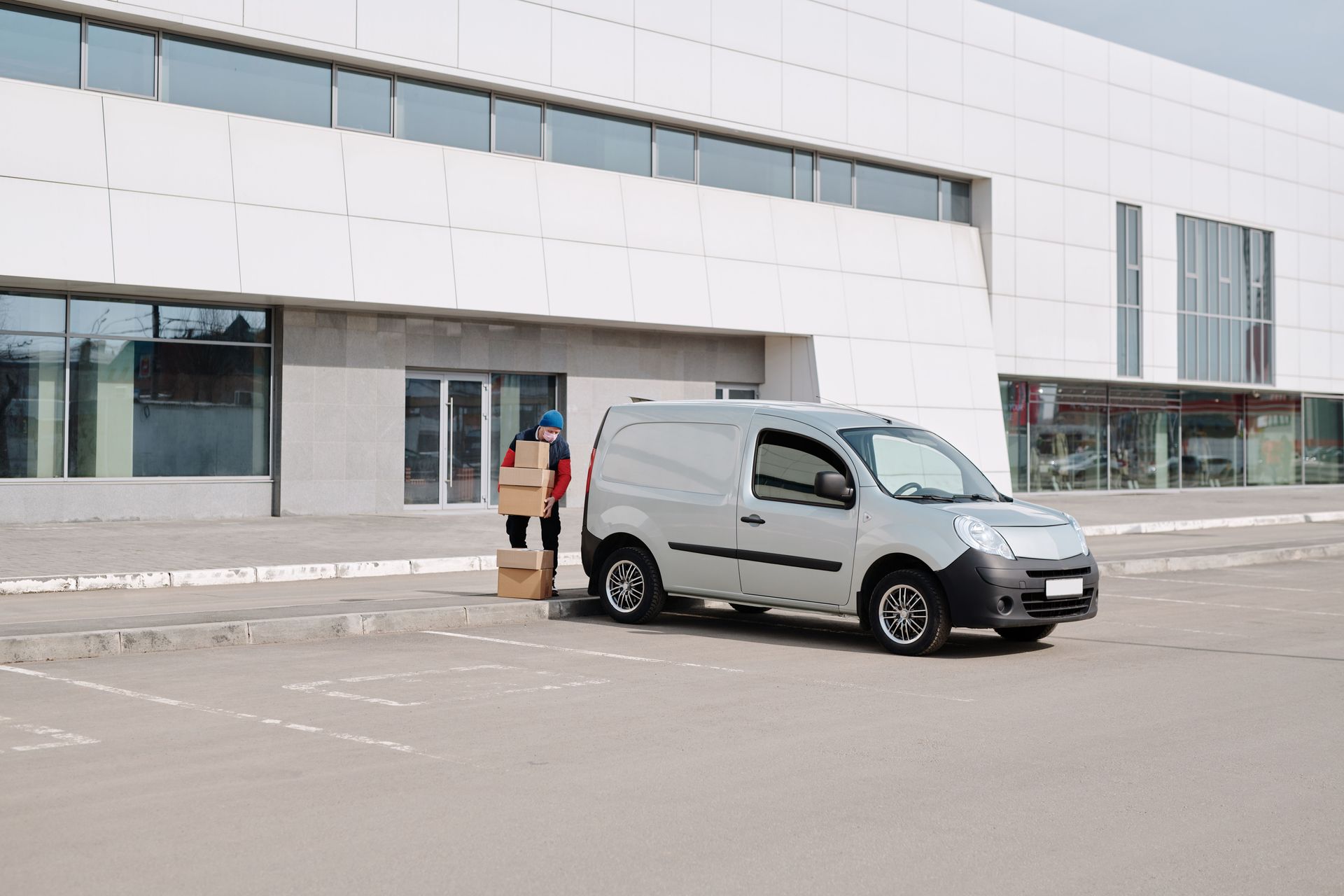 White van parked outside a large building, with a person standing nearby in the lot.