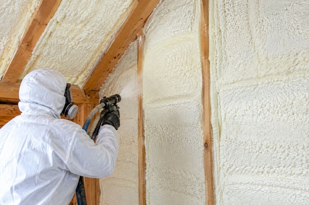 Contractor applying spray foam insulation to a wall. 
