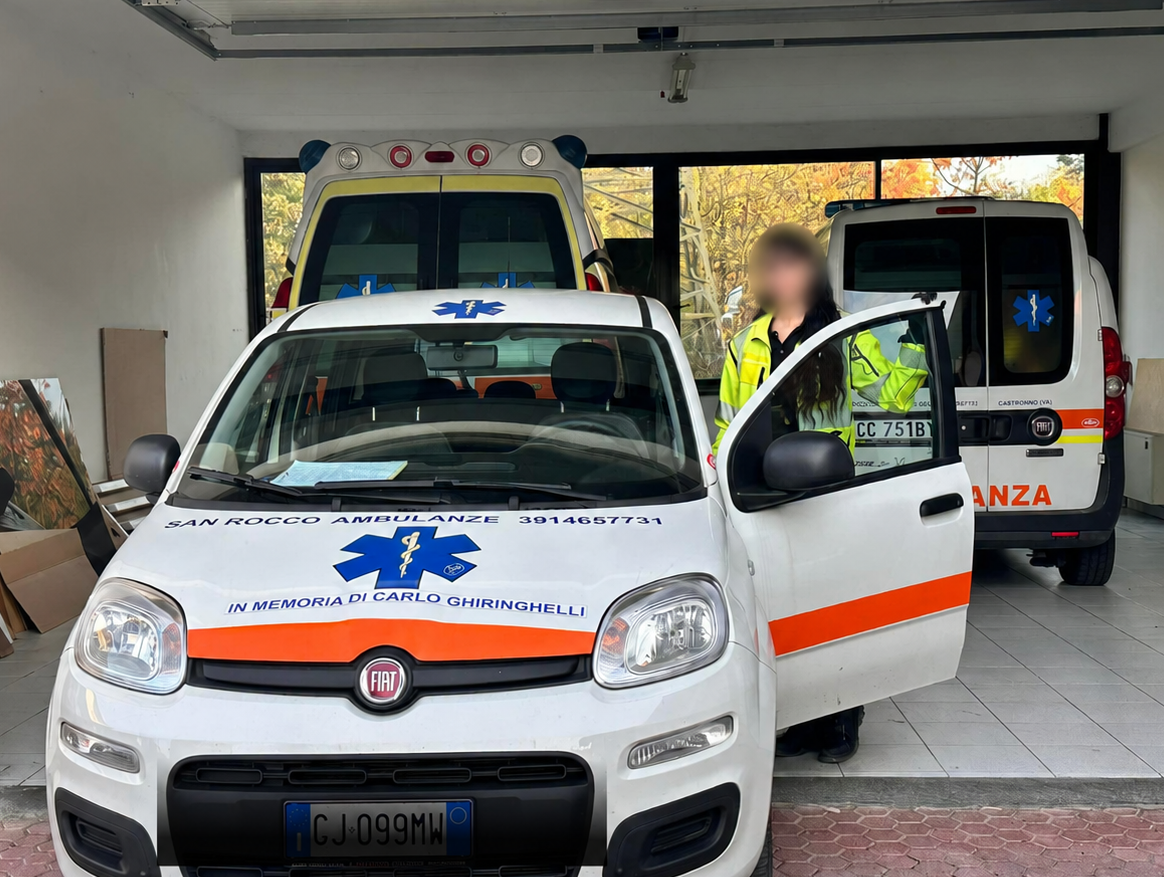 Ambulanze parcheggiate in un garage, con una porta aperta e una persona in piedi accanto.