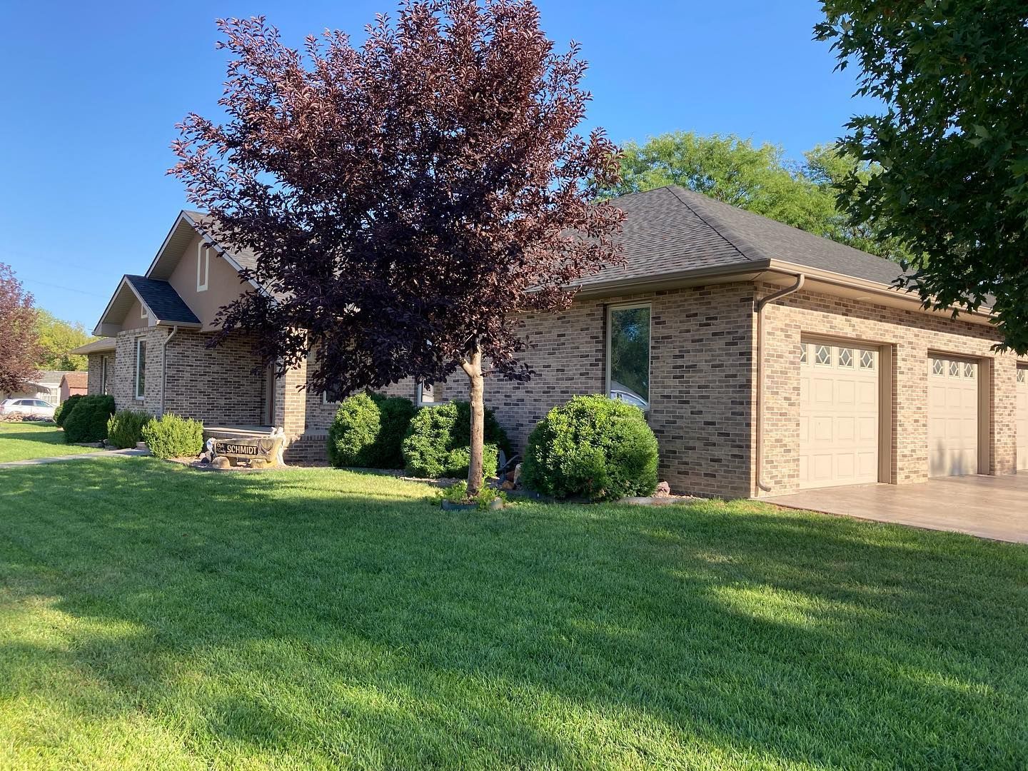 a brick house with a garage and a tree in front of it
