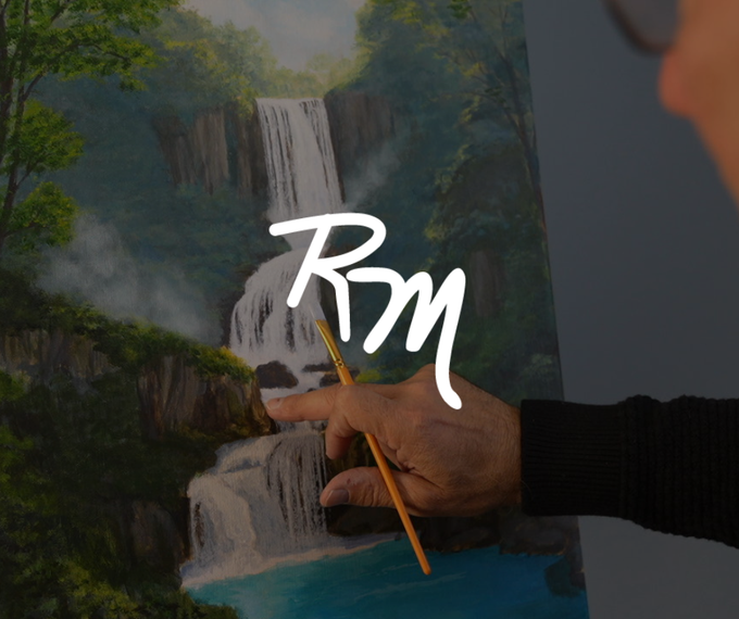 A person paints a layered waterfall landscape on canvas with a fine brush.