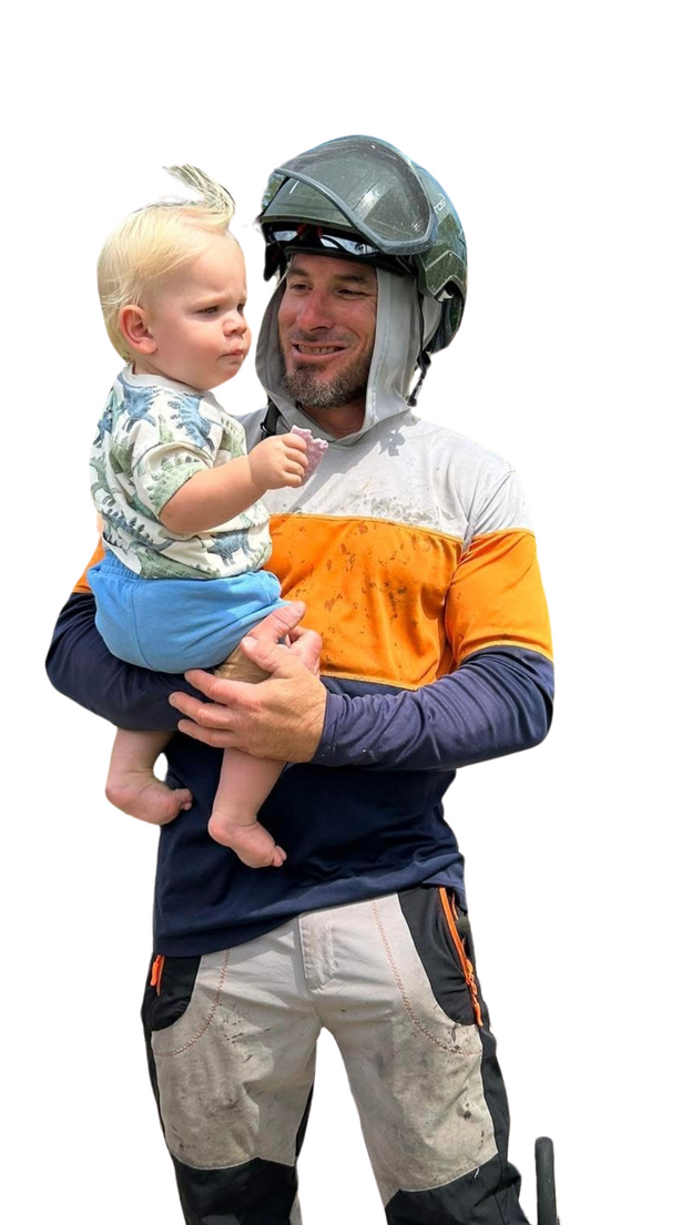 A man wearing a helmet is holding a baby in his arms.