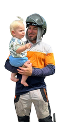 A man wearing a helmet is holding a baby in his arms.