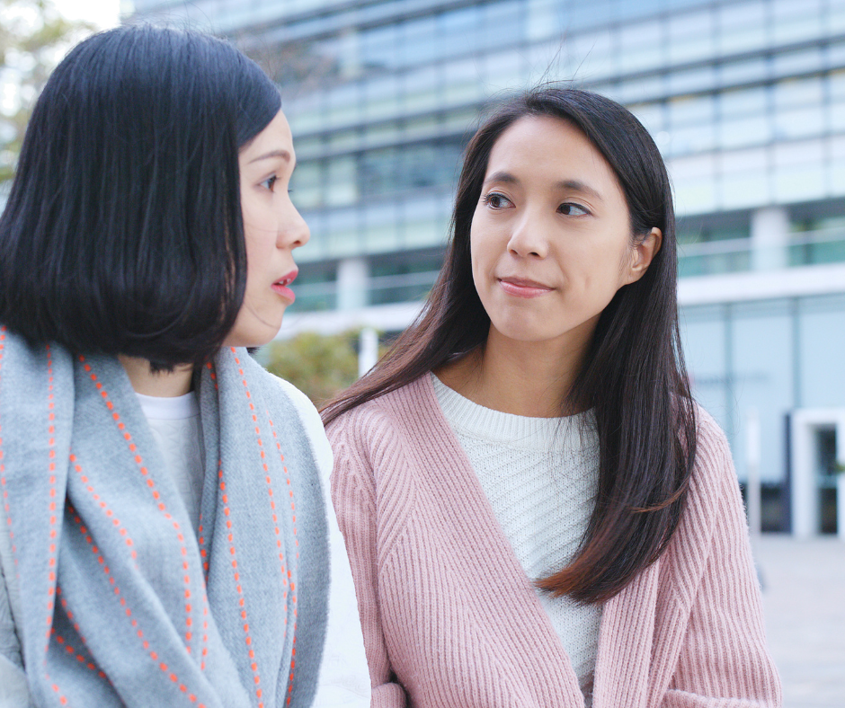 Two women are talking to each other outside.