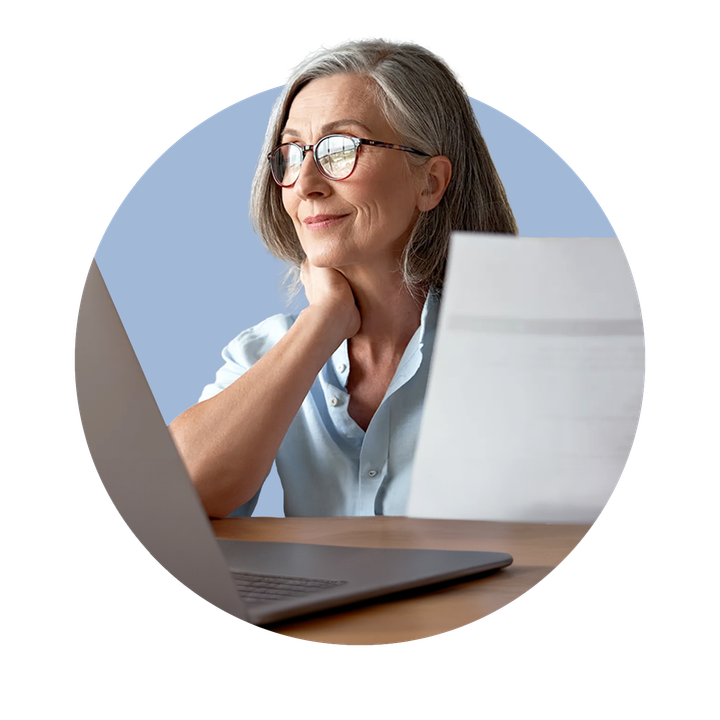 Professional woman holding paper and with laptop in front of her, facing towards a window