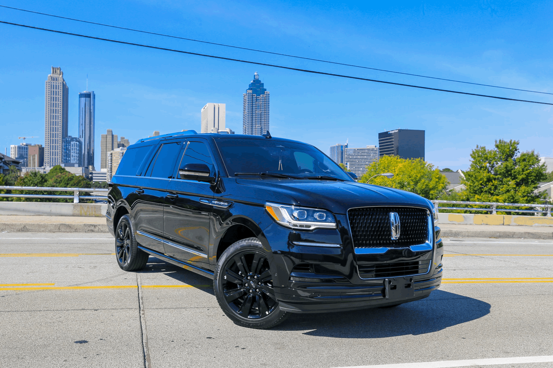 A black lincoln navigator is parked on the side of the road in front of a city skyline.
