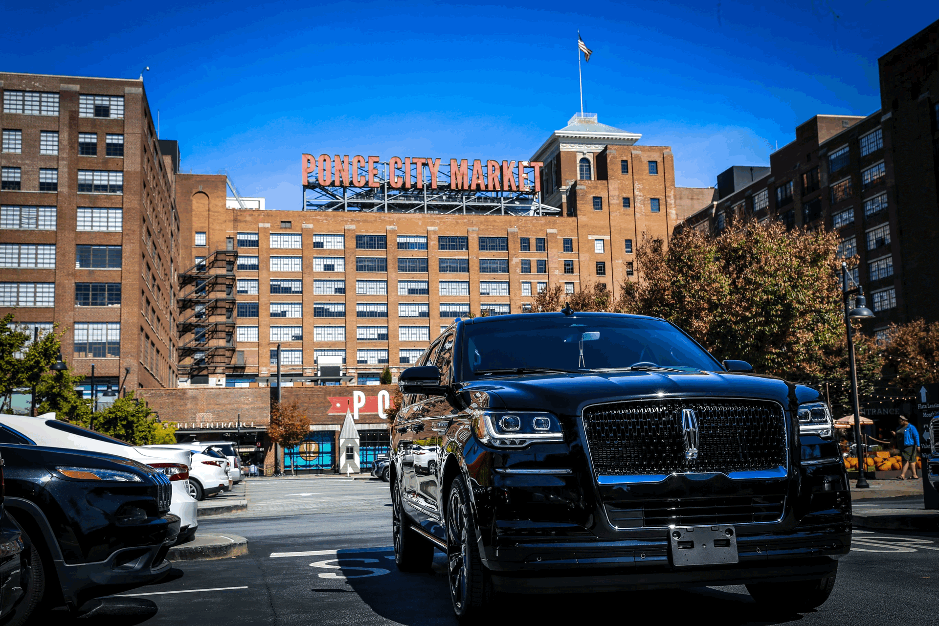 A black car is parked in front of a large building.