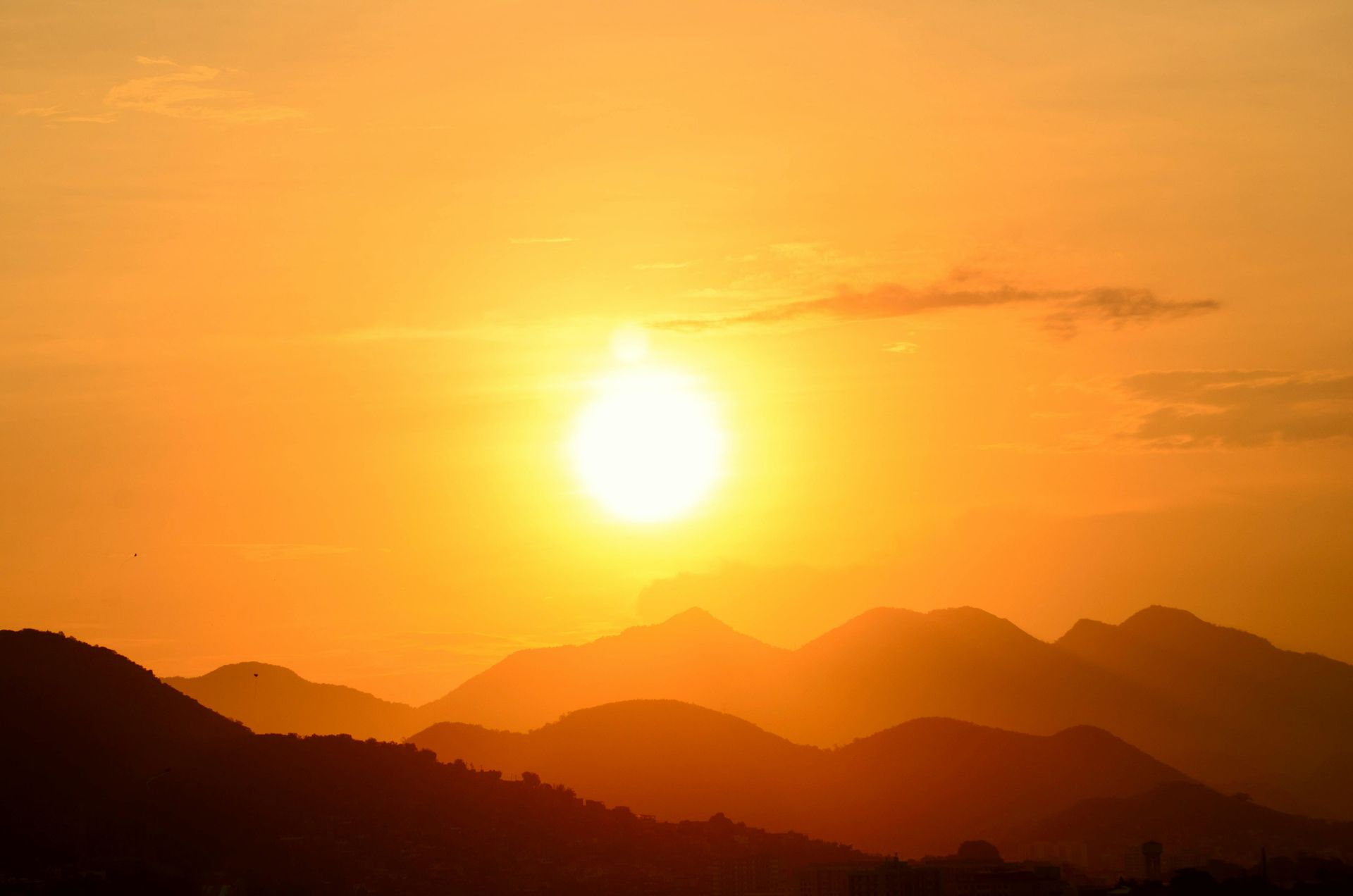 Golden sunset over silhouetted mountains, casting warm light.