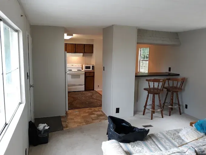 Interior view of a home with a kitchen visible through an opening. There's a bar with stools, and painted walls.