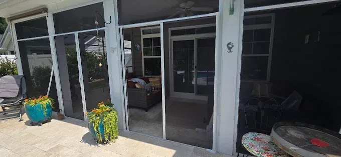 Screened patio with potted plants, furniture, and access to an interior room.