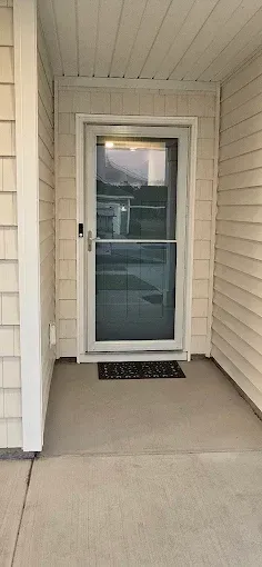 Front door with a glass storm door, a welcome mat on the porch, and a Ring doorbell.