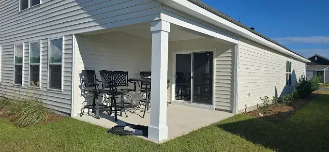 Exterior view of a house with a covered patio, patio furniture, and sliding glass door.