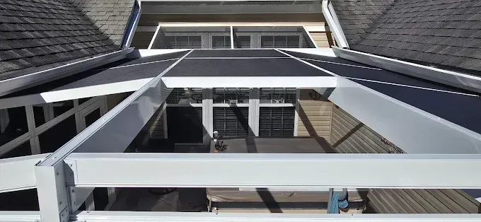 View from above of a building with a skylight-like structure, grey roof, and white beams.