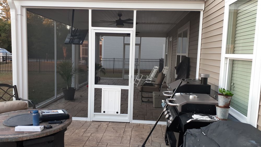 Screened-in porch with outdoor grill, furniture, and a door leading to a backyard.