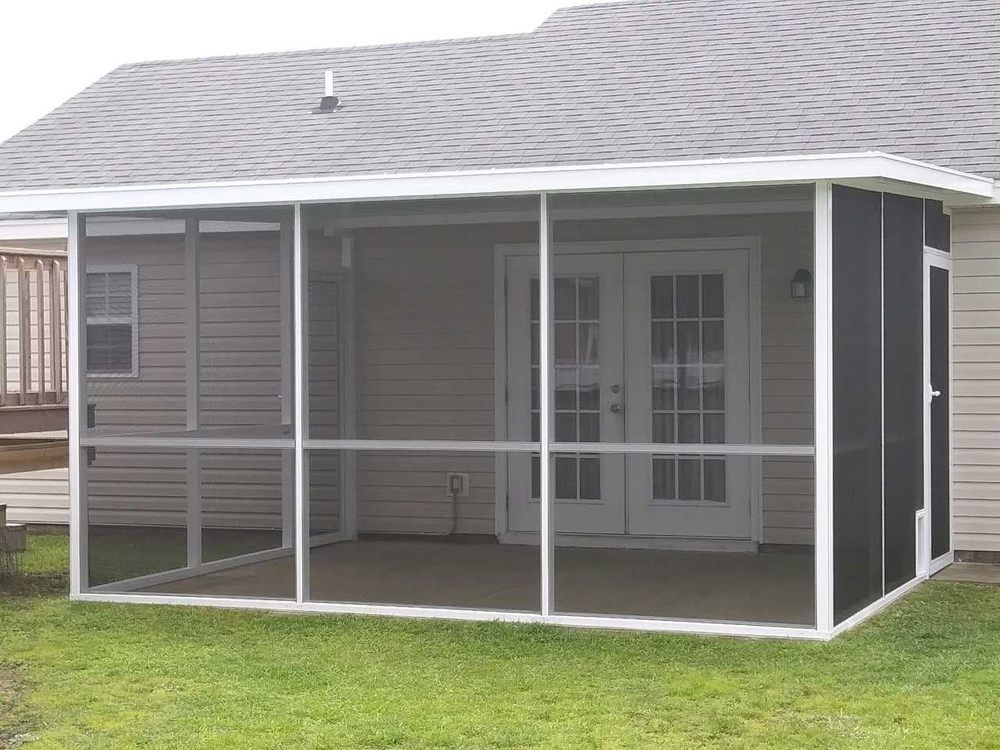 Screened-in porch attached to a light beige house with white trim, doors, and a gray roof; green lawn in front.