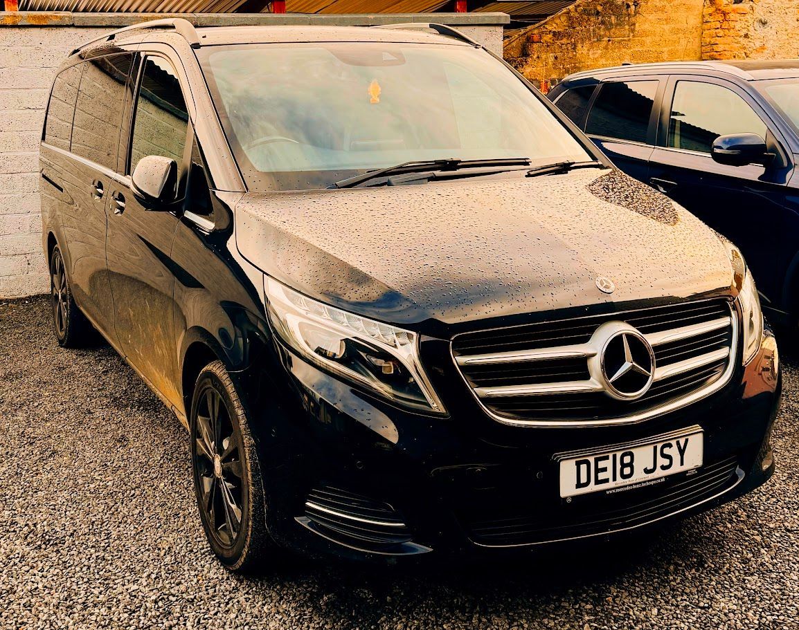 Black Mercedes van parked outdoors in the rain, front view with UK license plate visible