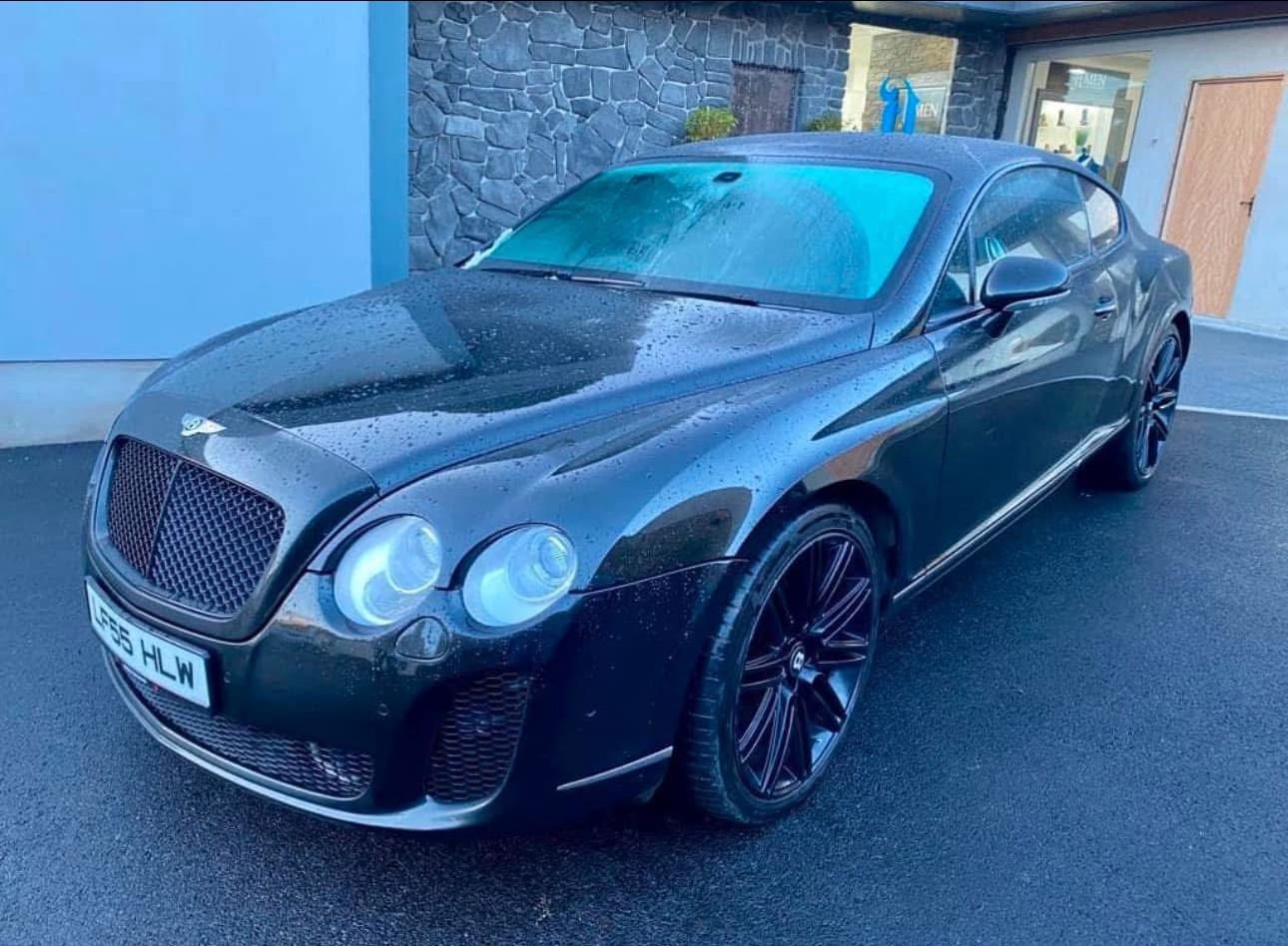 Black Bentley coupe parked outside a house on a driveway