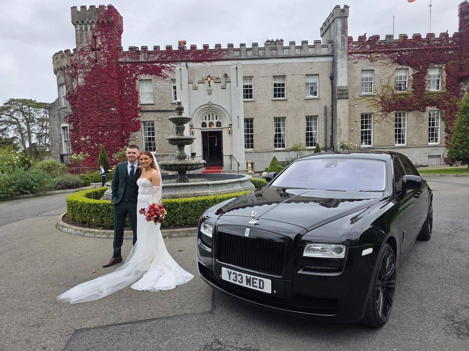 Bride and black luxury car outside a grand stone manor with ivy-covered walls