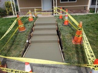 A concrete walkway is being built in front of a house.