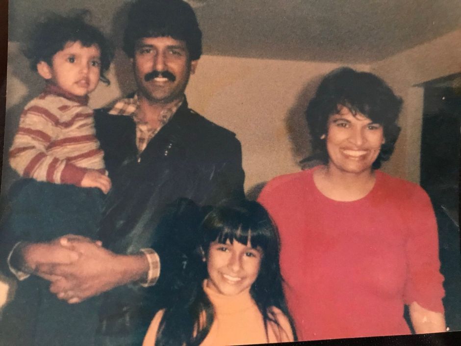Family of four posing indoors, with two adults and two children smiling at the camera.