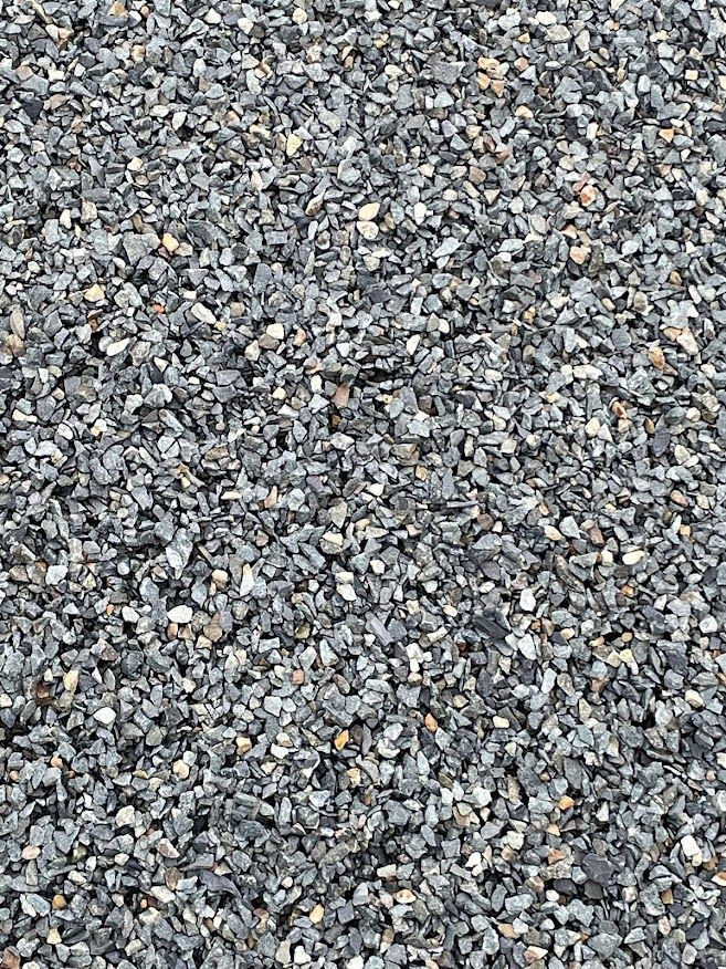 a pile of gravel is sitting on the ground . Screenings rock materials