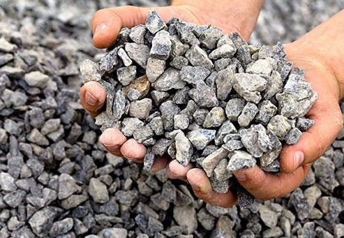 A person is holding a pile of gravel in their hands.