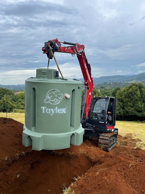 Excavator lifting and installing a concrete septic tank into a prepared trench— TCP Plumbing in Tunglebung, NSW