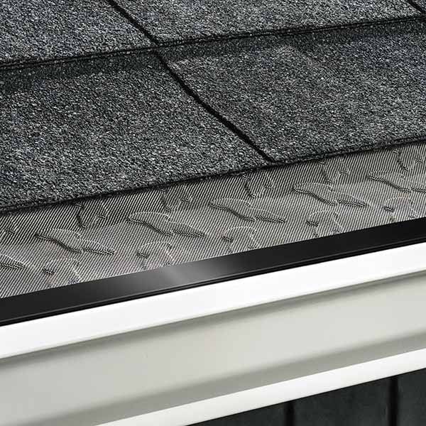 Hand spraying a roof gutter with a pressure washer from a rooftop walkway