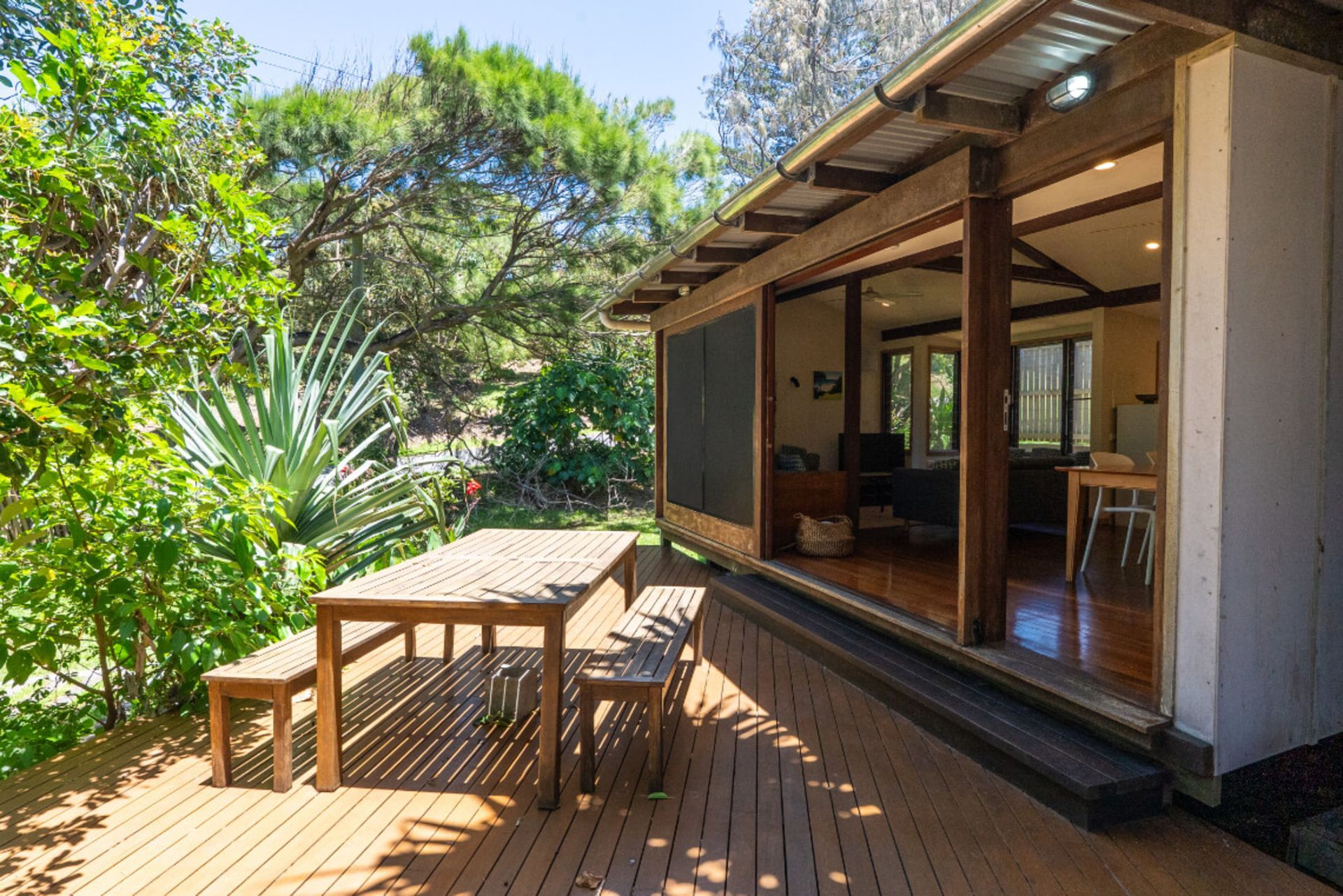 Wooden deck with outdoor table and chairs beside a house in a sunny garden
