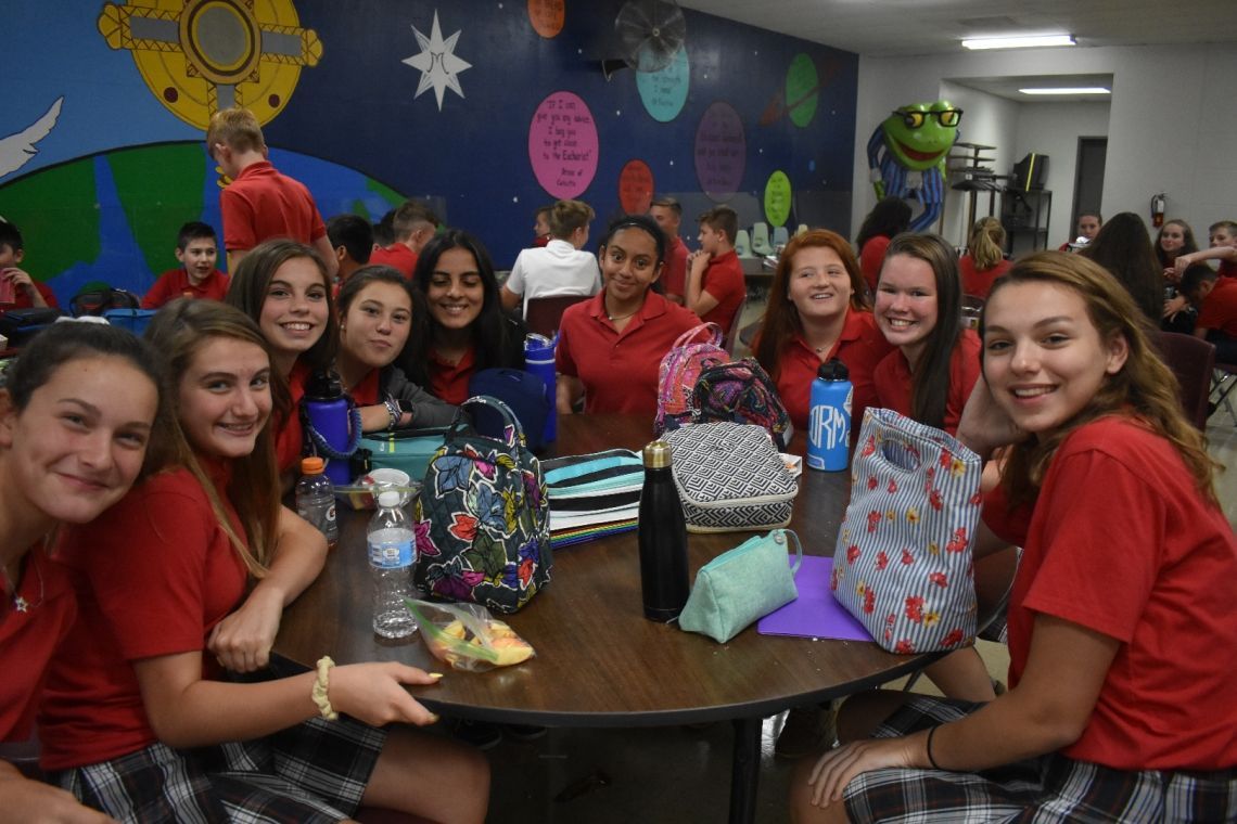 A group of girls in red shirts are sitting around a table
