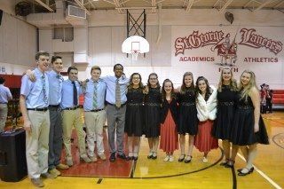 A group of people are posing for a picture on a basketball court.