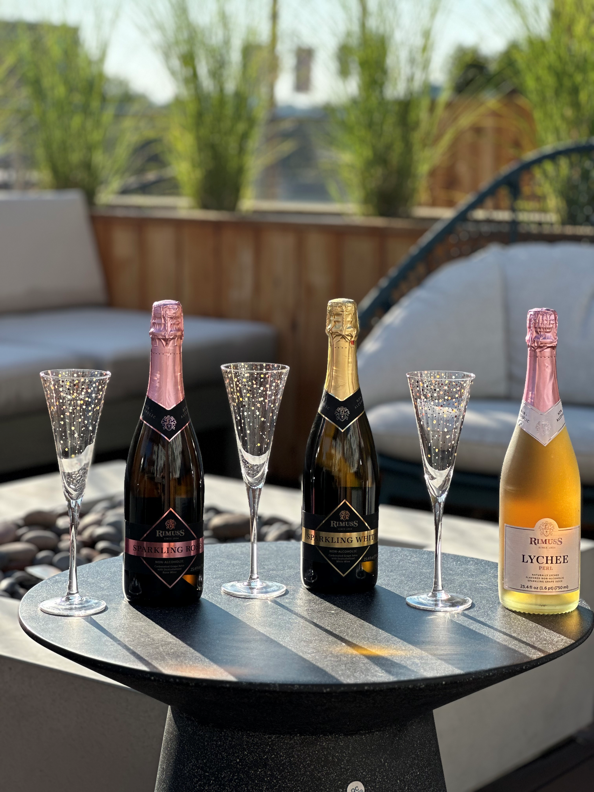 Four bottles of champagne and wine glasses are sitting on a table.