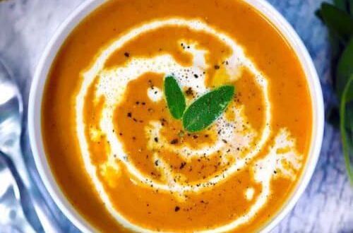A bowl of soup with whipped cream and sage on top.