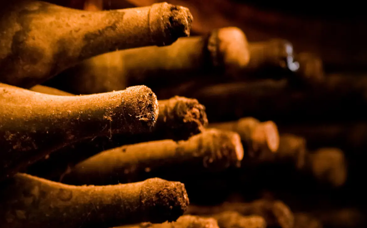 A bunch of old bottles of wine are stacked on top of each other.