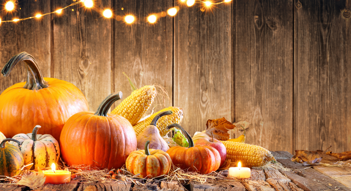 A wooden table topped with pumpkins , corn , and candles.