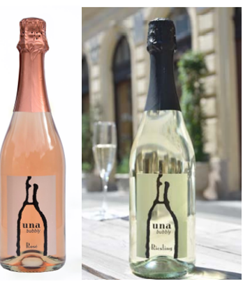 A bottle of una bubbly sits on a table next to a glass