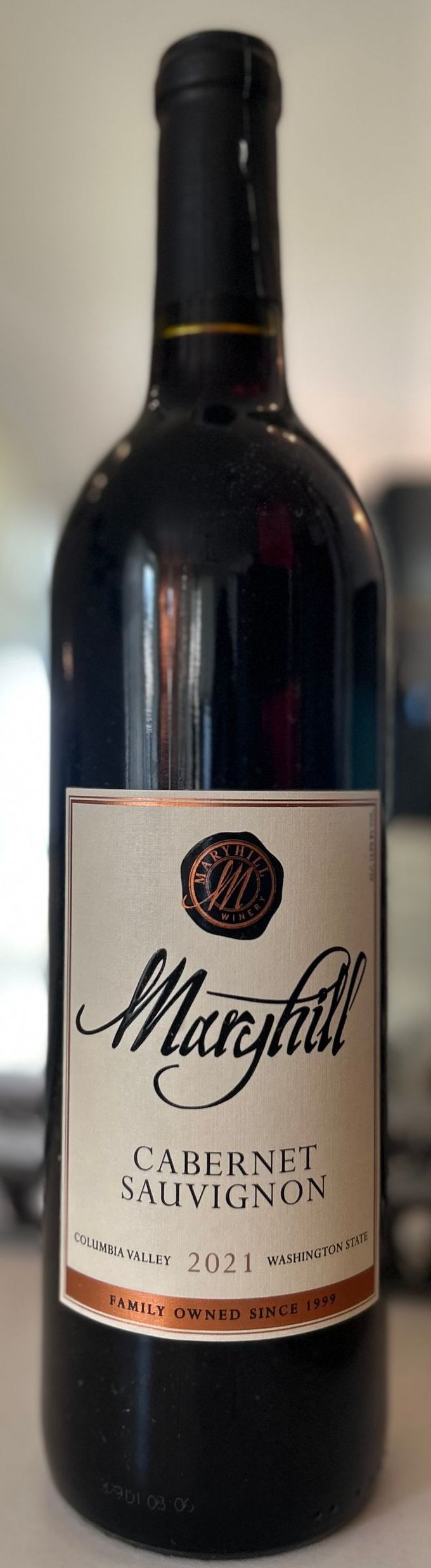 A bottle of wine with a white label is sitting on a table.