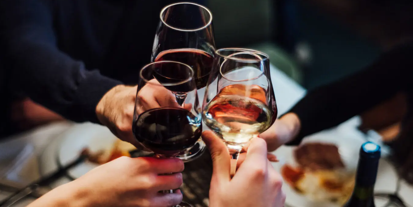 A group of people are toasting with wine glasses at a table.