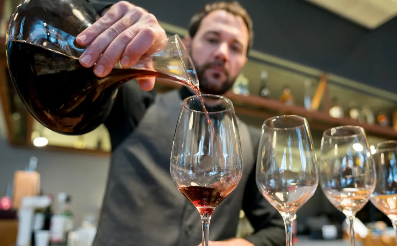 A man is pouring wine into a glass.